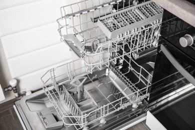 Photo of Open clean empty dishwasher in kitchen, closeup
