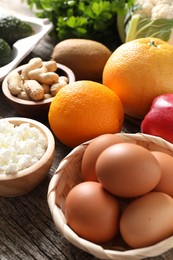 Photo of Healthy meal. Different vegetables and raw eggs on wooden table, closeup