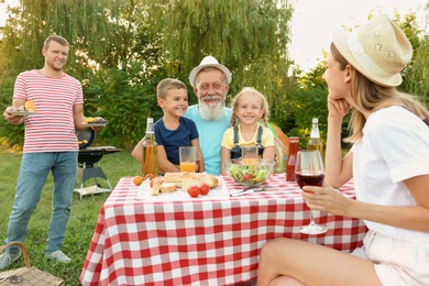 Photo of Happy family having barbecue in park on sunny day