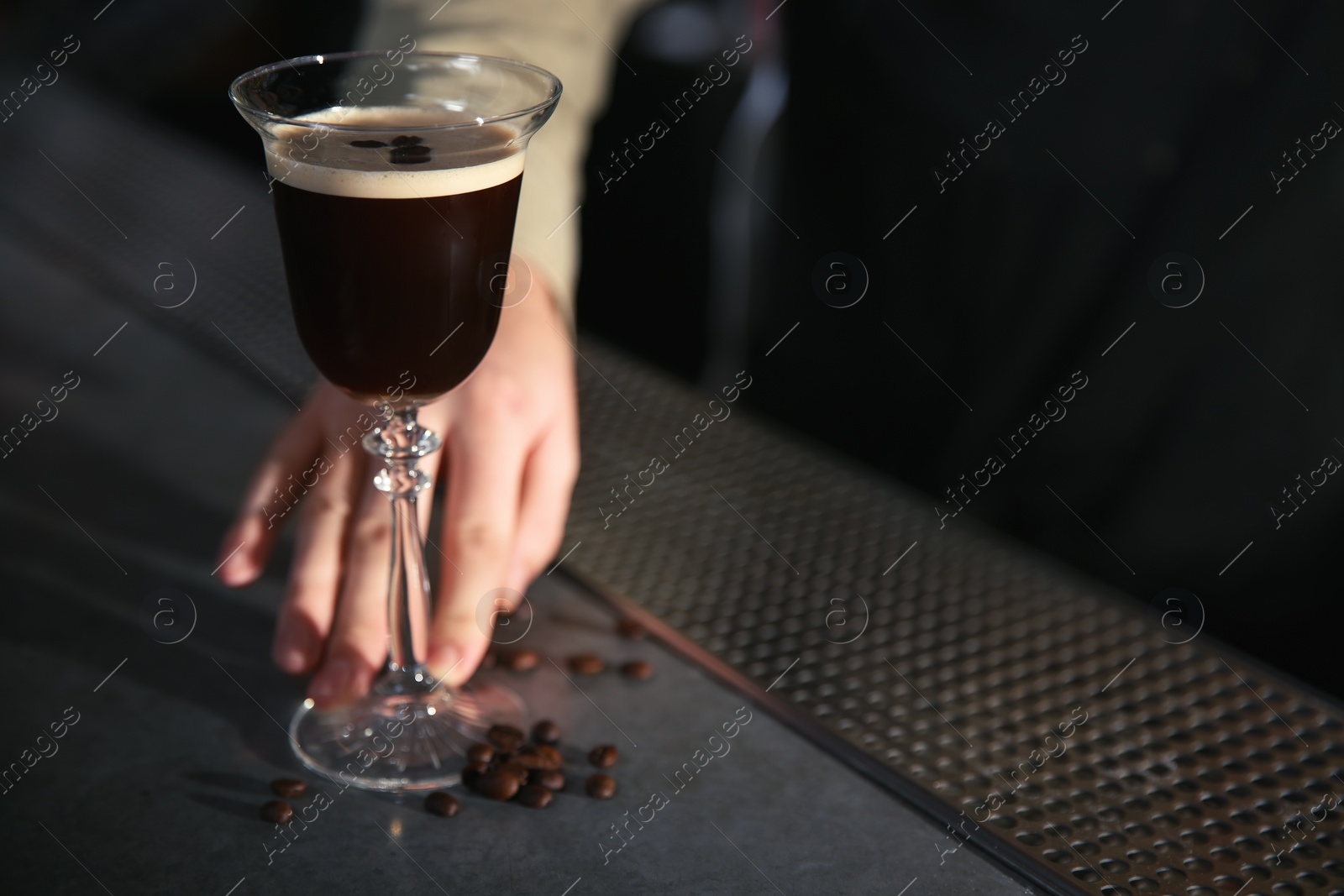 Photo of Barman serving espresso martini cocktail at counter, closeup. Space for text