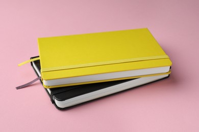 Photo of Yellow and black notebooks on light pink background