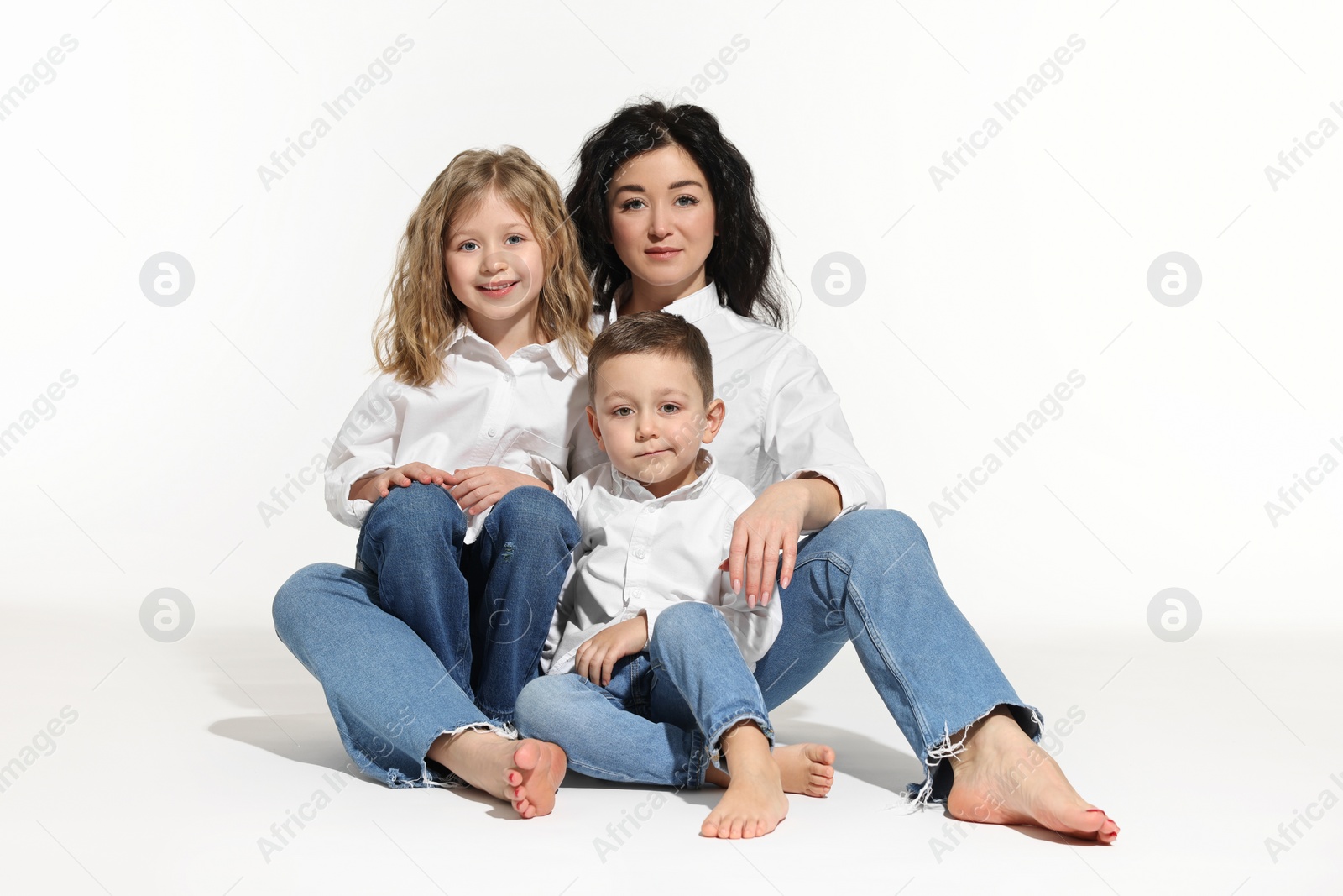 Photo of Little children with their mother sitting together on white background