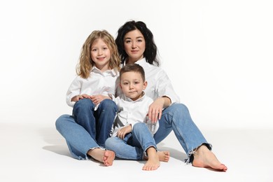 Little children with their mother sitting together on white background