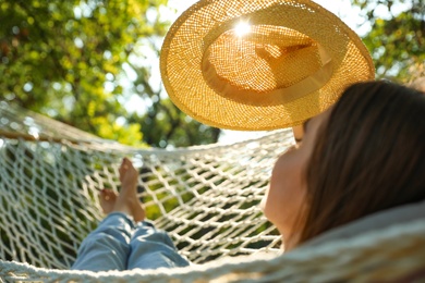 Photo of Young woman with hat resting in comfortable hammock at green garden, closeup