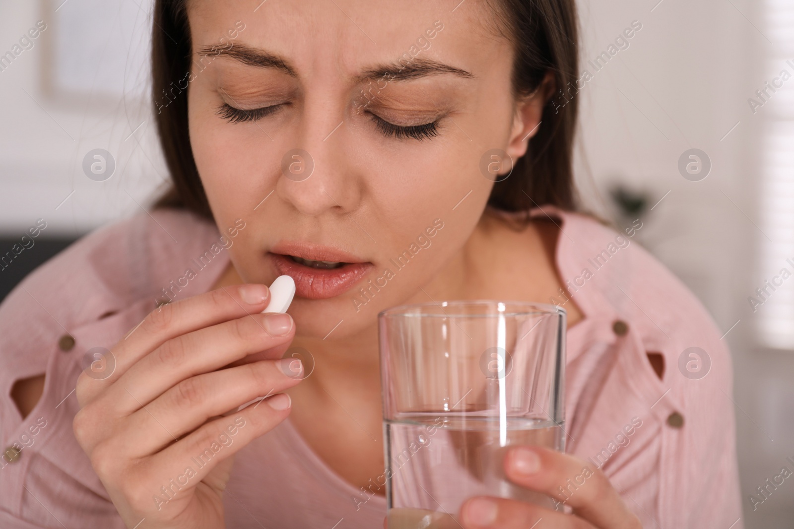 Photo of Sad young woman taking abortion pill at home, closeup