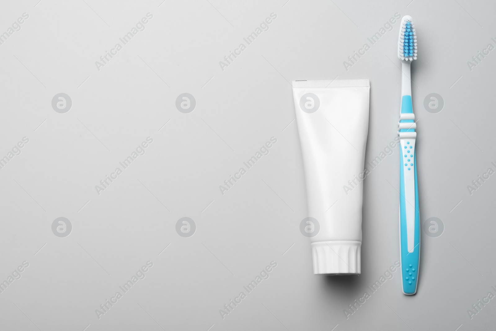 Photo of Blank tube of toothpaste and brush on white background, top view with space for text