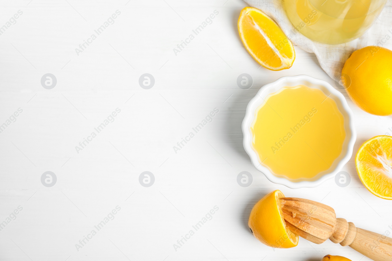 Photo of Freshly squeezed lemon juice on white wooden table, flat lay. Space for text