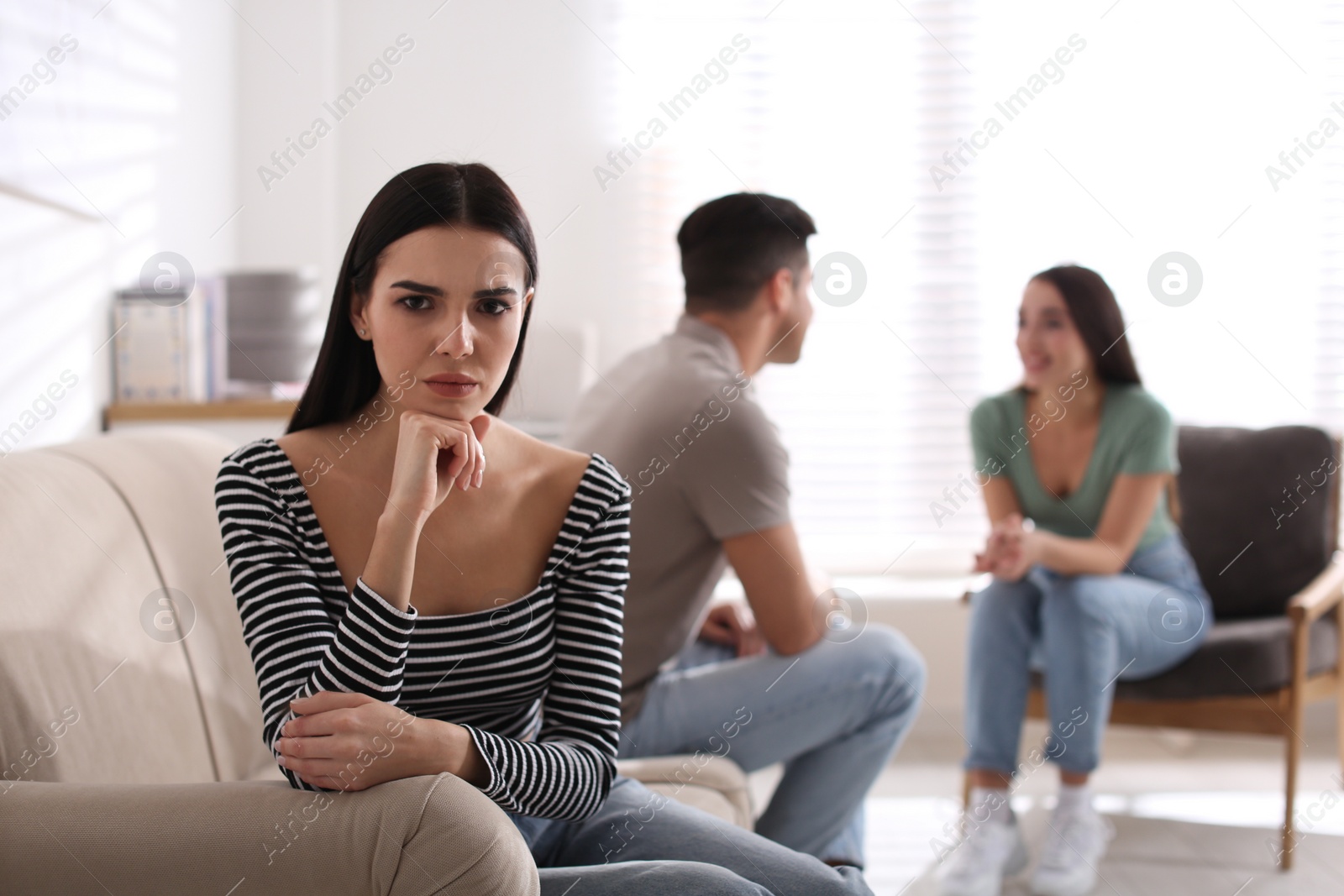 Photo of Unhappy woman feeling jealous while couple spending time together at home