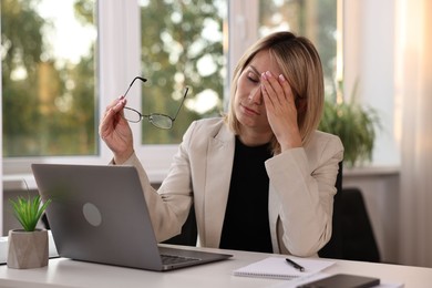 Photo of Overwhelmed woman sitting at table in office