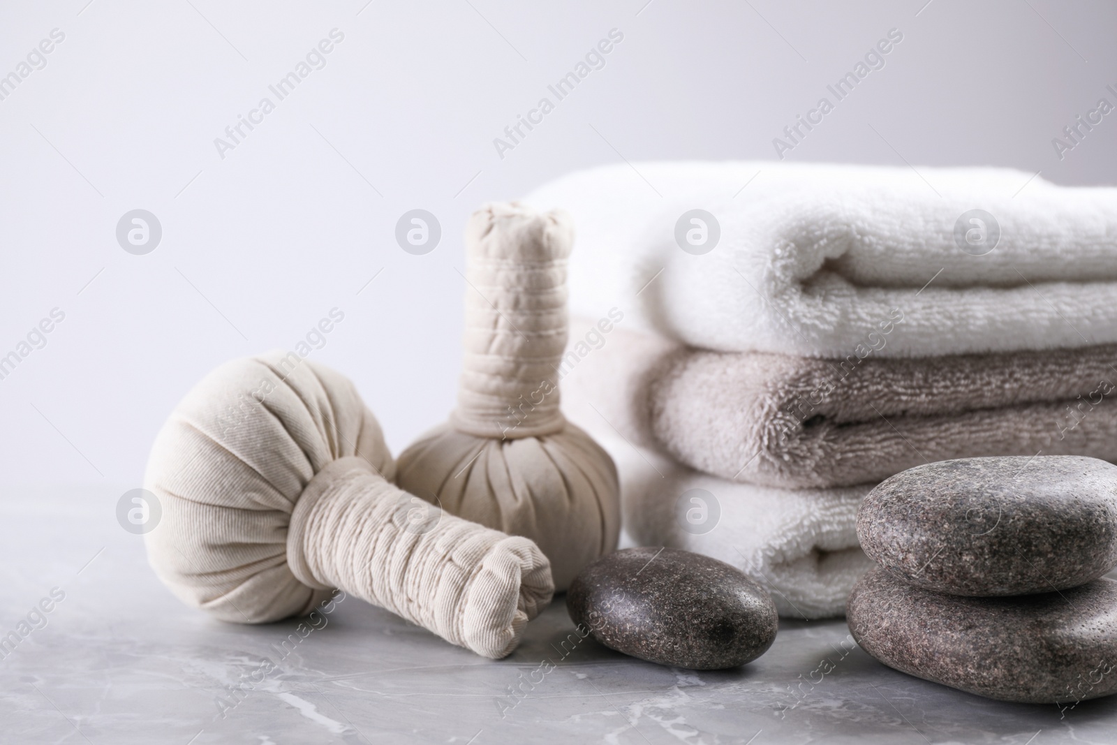 Photo of Fresh towels, spa stones and herbal bags on grey table, space for text