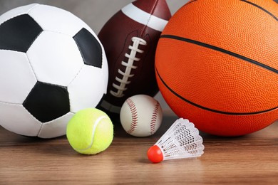 Set of different sport balls and shuttlecock on wooden table