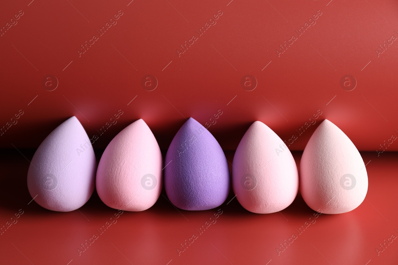 Photo of Many colorful makeup sponges on red background