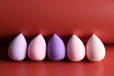 Photo of Many colorful makeup sponges on red background