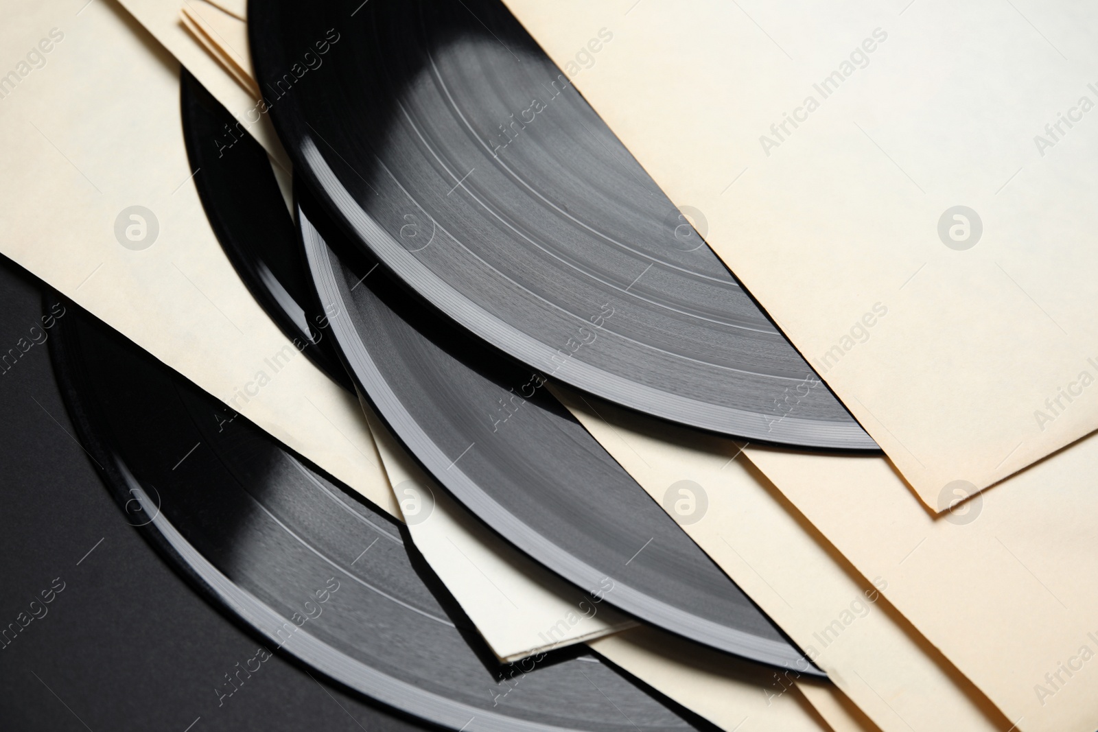 Photo of Vintage vinyl records in paper sleeves on black background, closeup