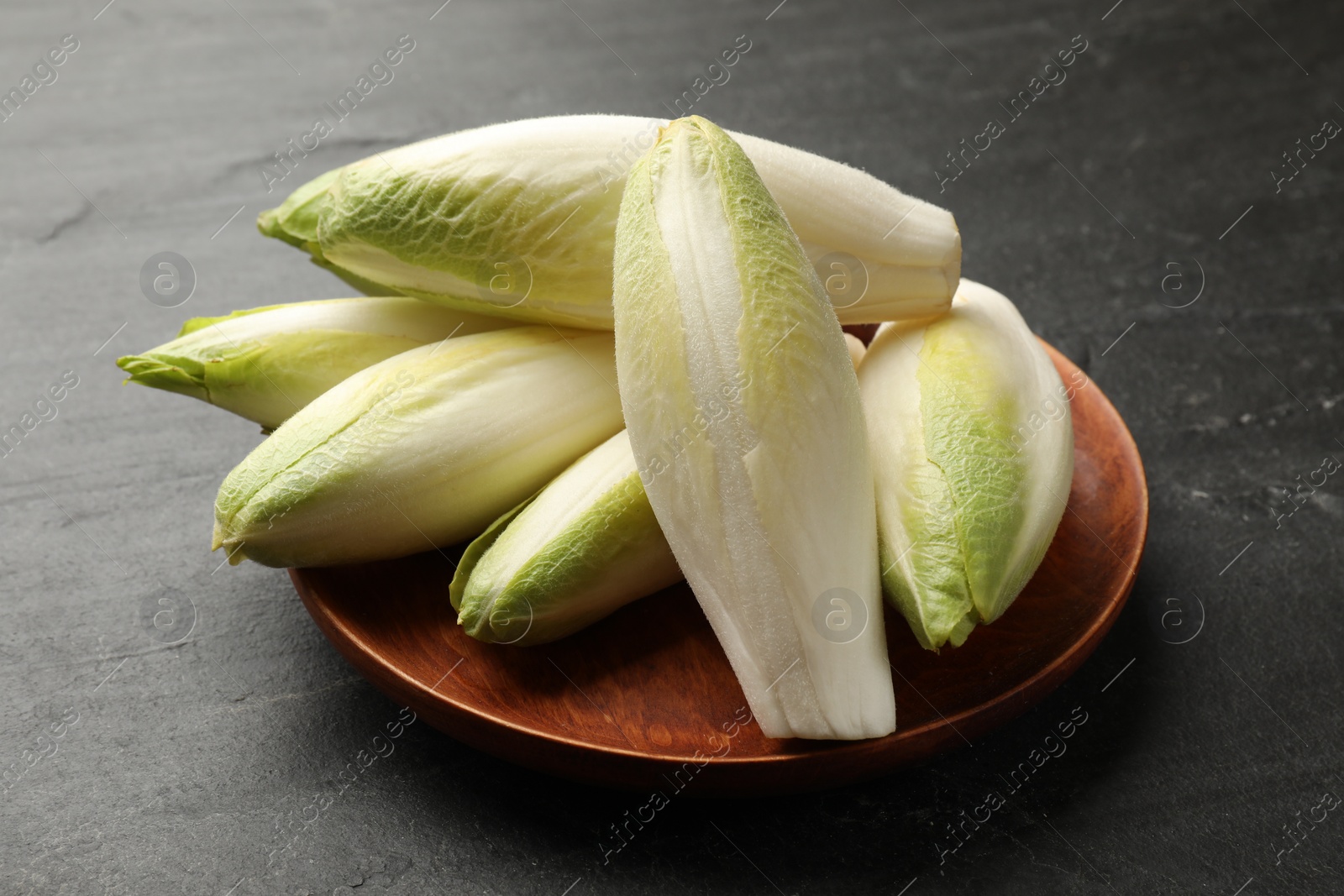 Photo of Fresh raw Belgian endives (chicory) on black table