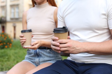 Coffee to go. Couple with paper cups outdoors, selective focus