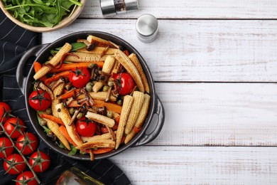 Tasty roasted baby corn with tomatoes, capers and mushrooms on white wooden table, flat lay. Space for text