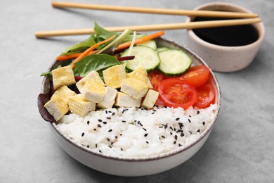Delicious poke bowl with vegetables, tofu and mesclun served on light grey table, closeup