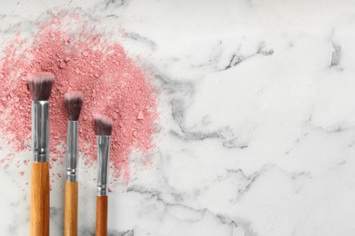 Photo of Makeup brushes and scattered eye shadow on white marble table, flat lay. Space for text