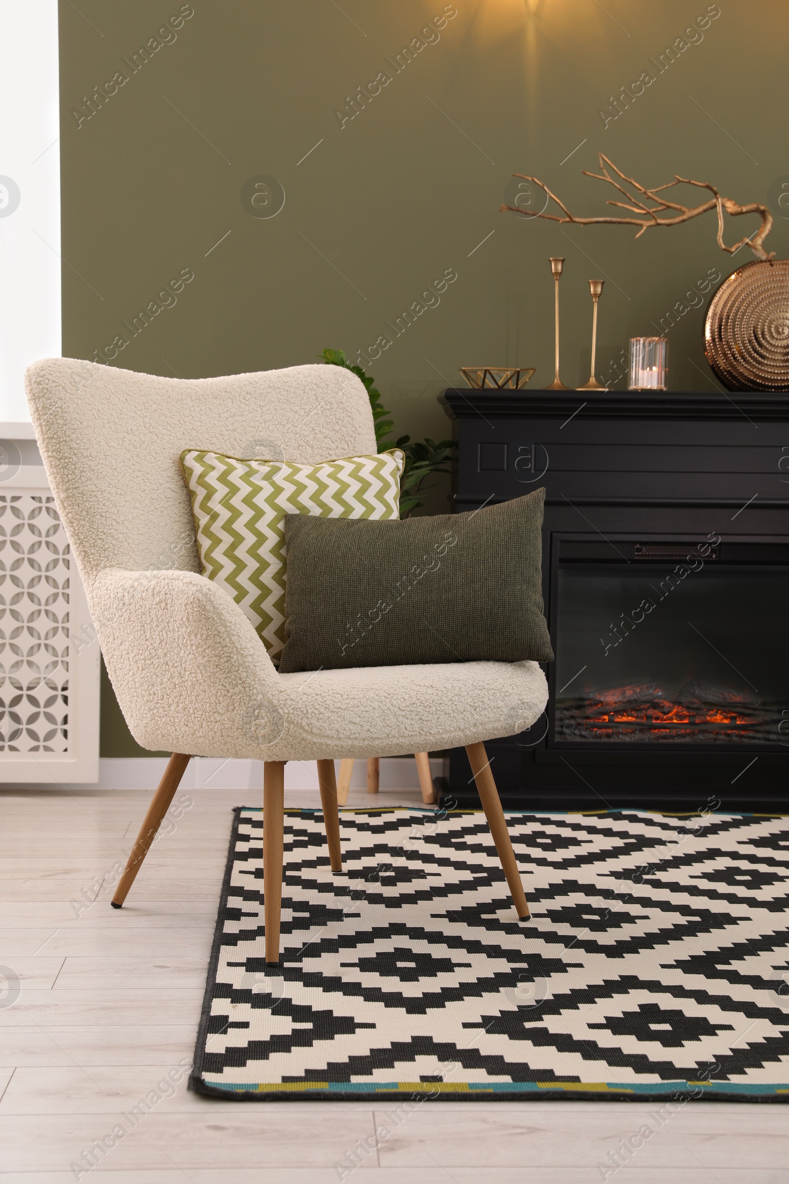 Photo of Armchair with cushions and beautiful fireplace in living room