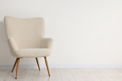 Comfortable armchair near white wall in room, space for text