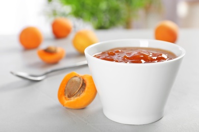 Photo of Bowl with tasty apricot jam on table