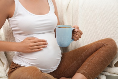 Pregnant woman drinking tea at home, closeup