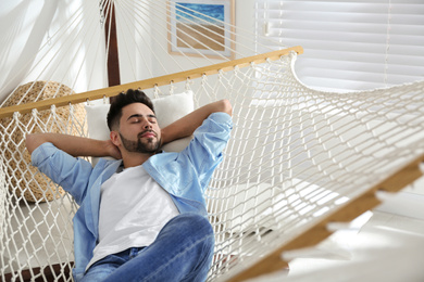 Young man relaxing in hammock at home