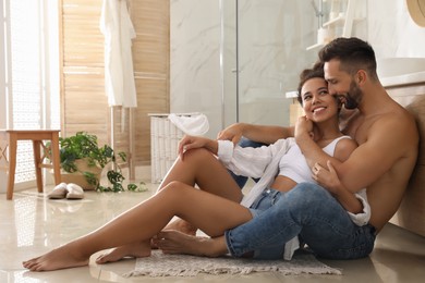 Photo of Lovely couple enjoying time together on floor in bathroom