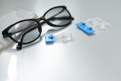 Single dose eye drops, glasses and fabric on white table. Space for text