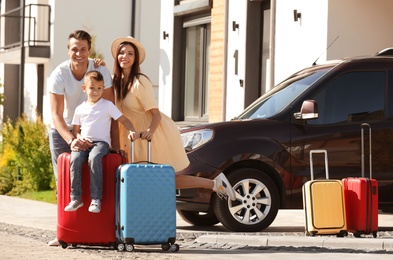 Photo of Happy family with suitcases near house outdoors. Moving day