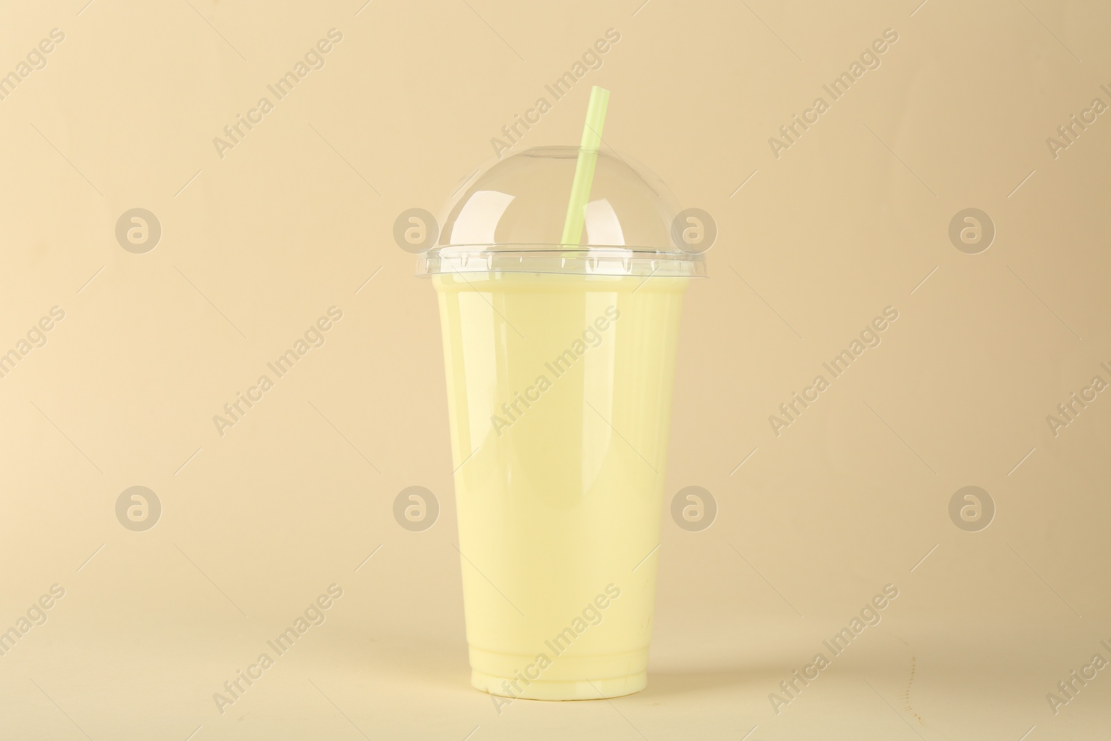 Photo of Plastic cup of tasty smoothie on beige background