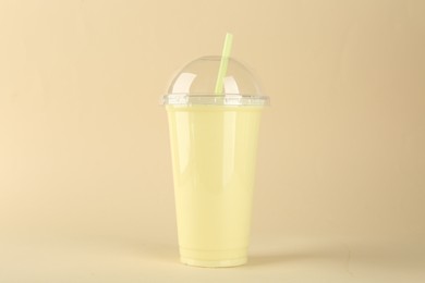 Photo of Plastic cup of tasty smoothie on beige background