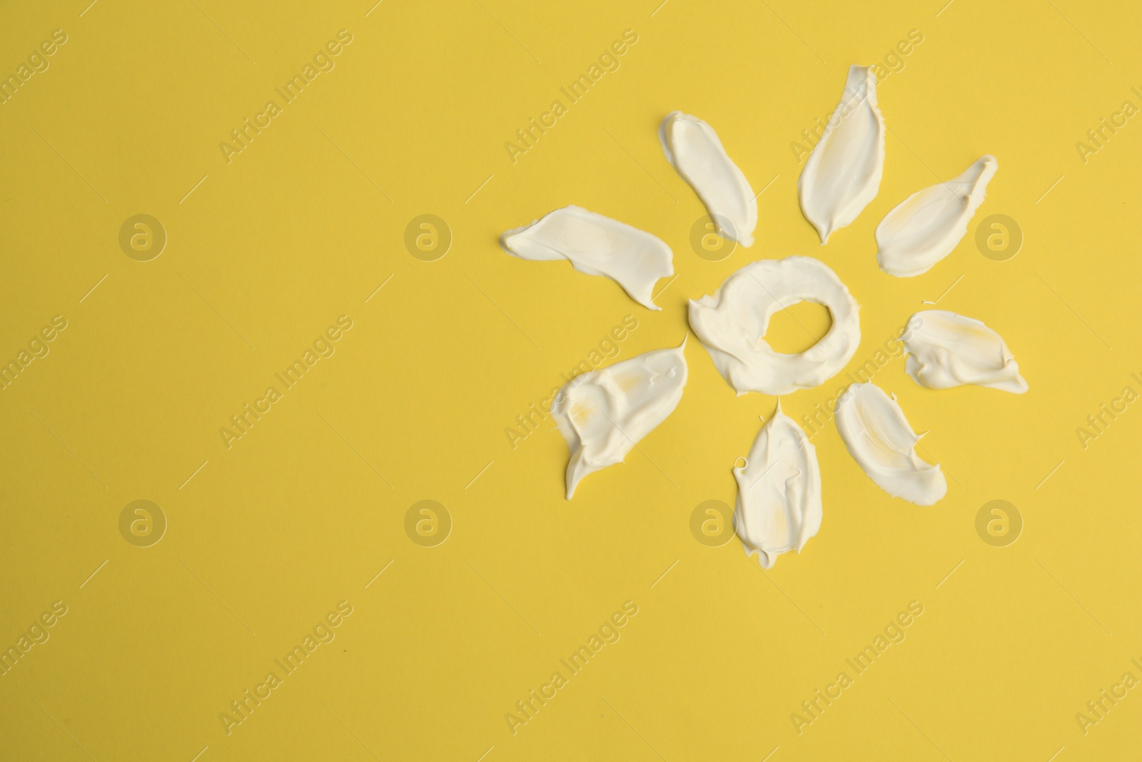 Photo of Drawing of sun with cream on yellow background, top view and space for text. Skin care and protection
