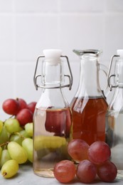 Different types of vinegar and grapes on grey table