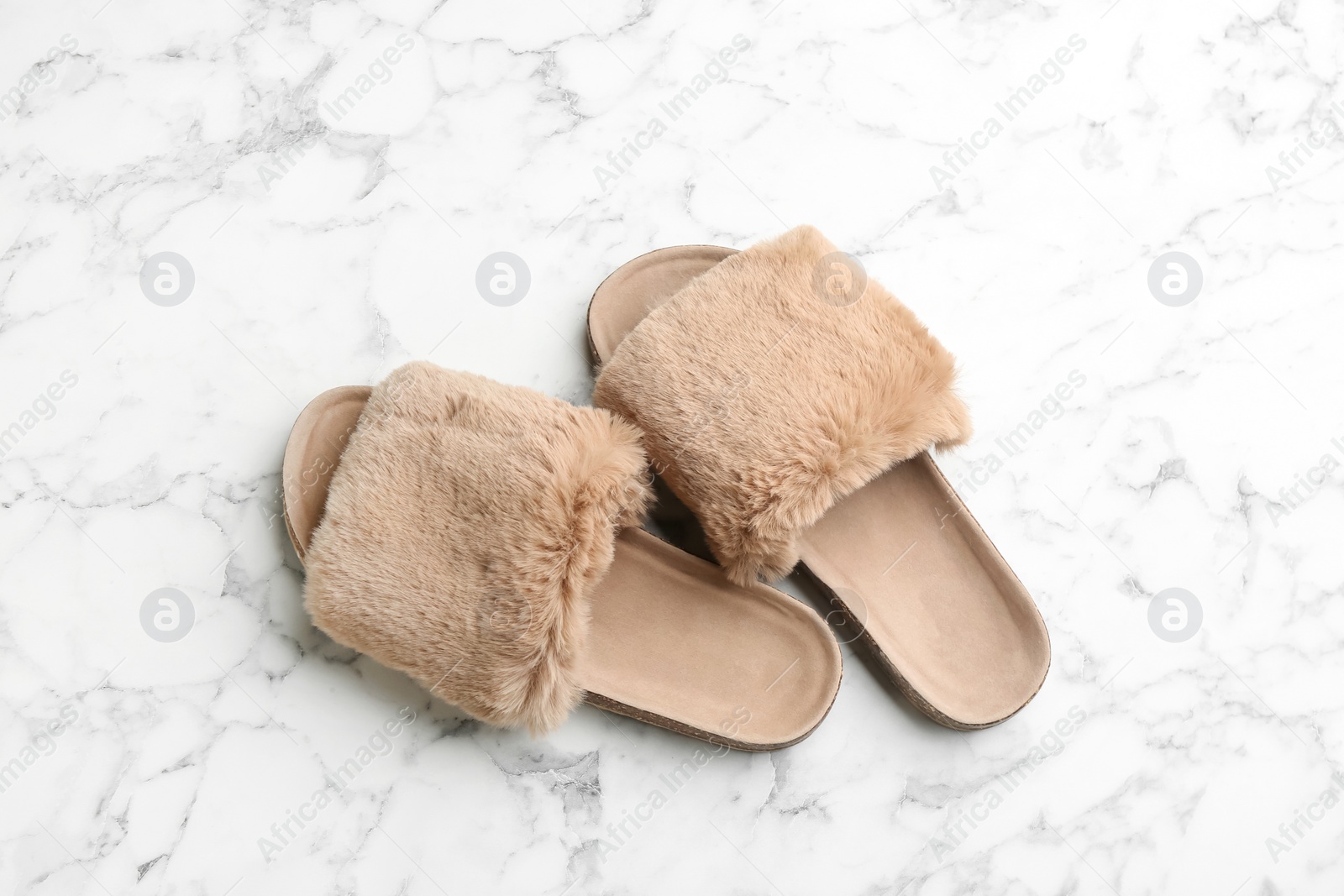 Photo of Pair of soft slippers on white marble background, flat lay
