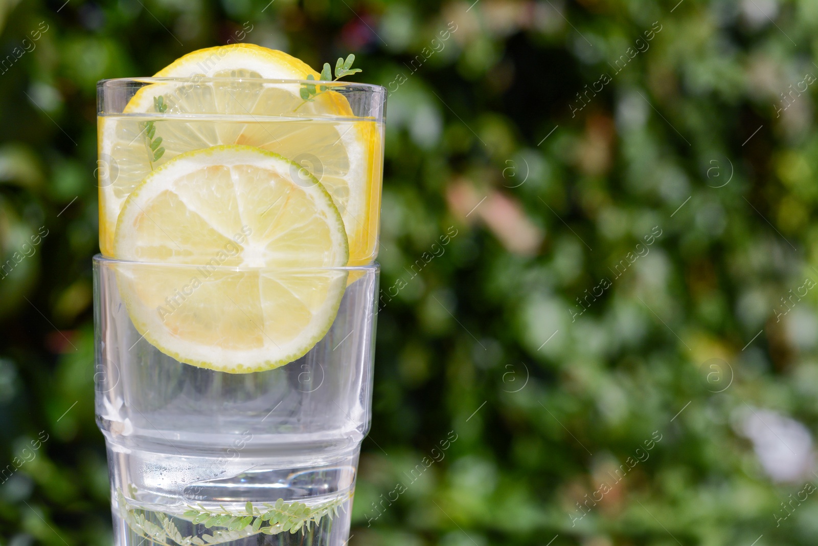 Photo of Delicious refreshing lemonade against green blurred background, closeup. Space for text