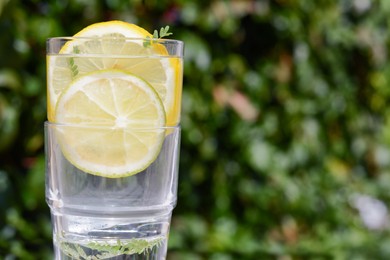 Photo of Delicious refreshing lemonade against green blurred background, closeup. Space for text