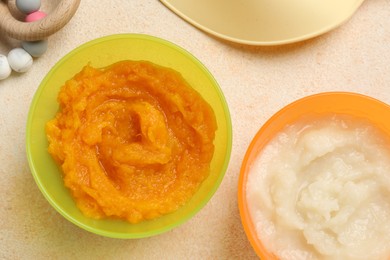 Photo of Baby food. Different tasty puree in bowls on beige textured table, flat lay