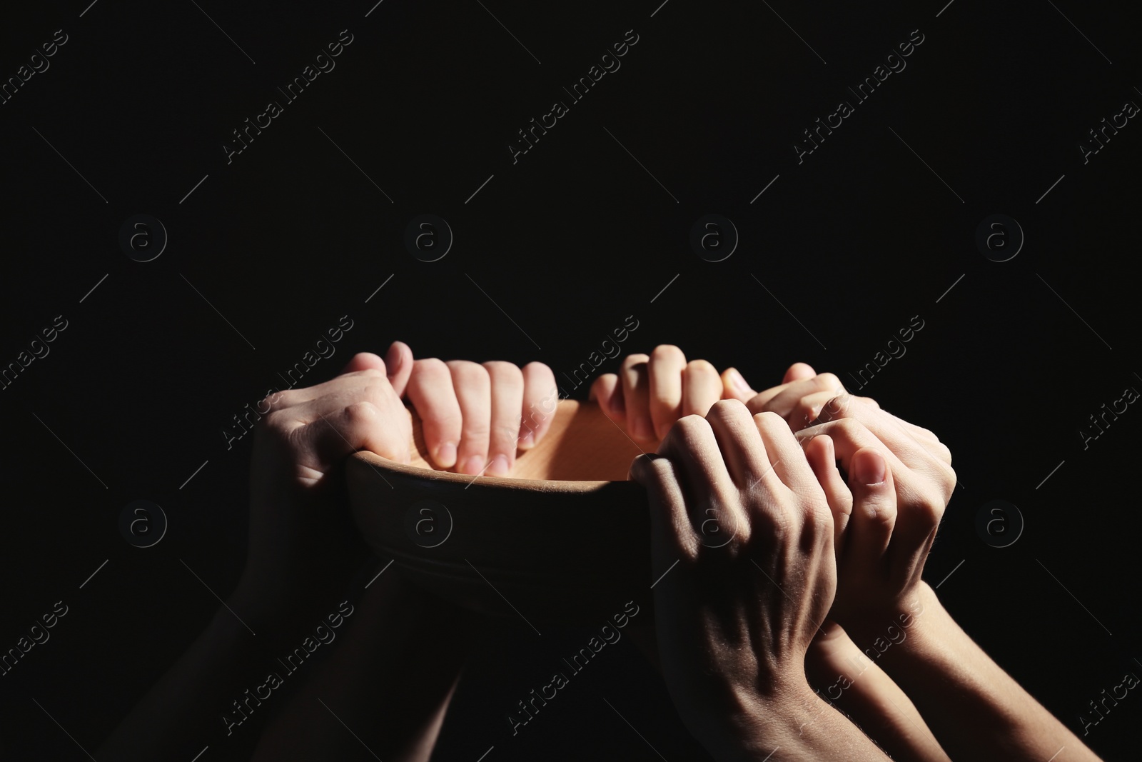 Photo of Poor people holding bowl on dark background, closeup