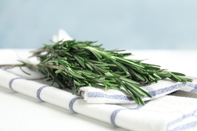 Photo of Fresh green rosemary and napkin on table