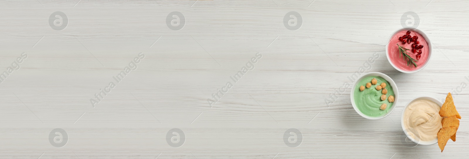 Image of Different delicious hummuses on white wooden table, flat lay with space for text. Banner design