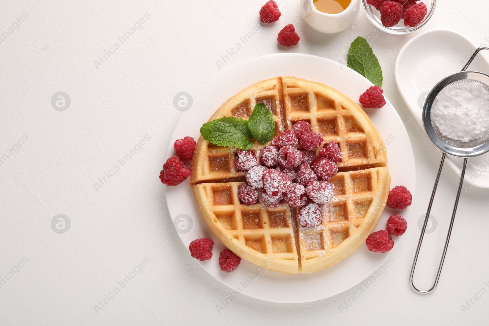 Photo of Tasty Belgian waffle with fresh raspberries, honey and powdered sugar on white table, flat lay. Space for text