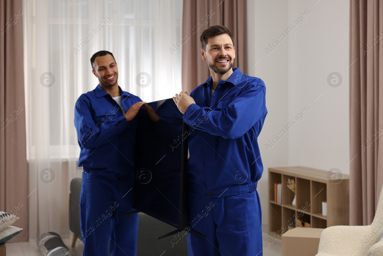 Photo of Male movers carrying plasma TV in new house