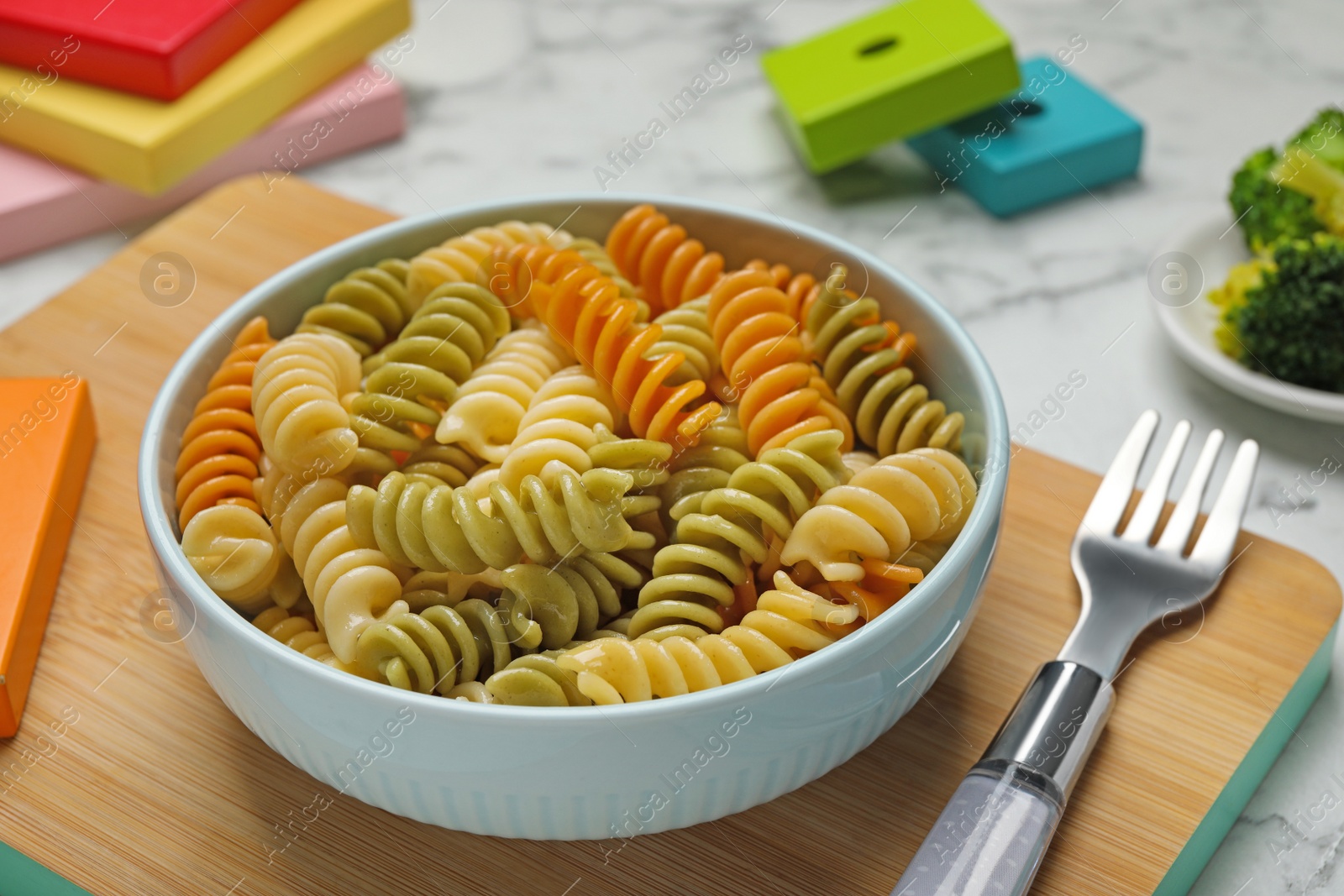 Photo of Bowl with tasty fusilli pasta on white marble table, closeup
