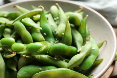 Photo of Green edamame beans in pods with sesame seeds in bowl, closeup