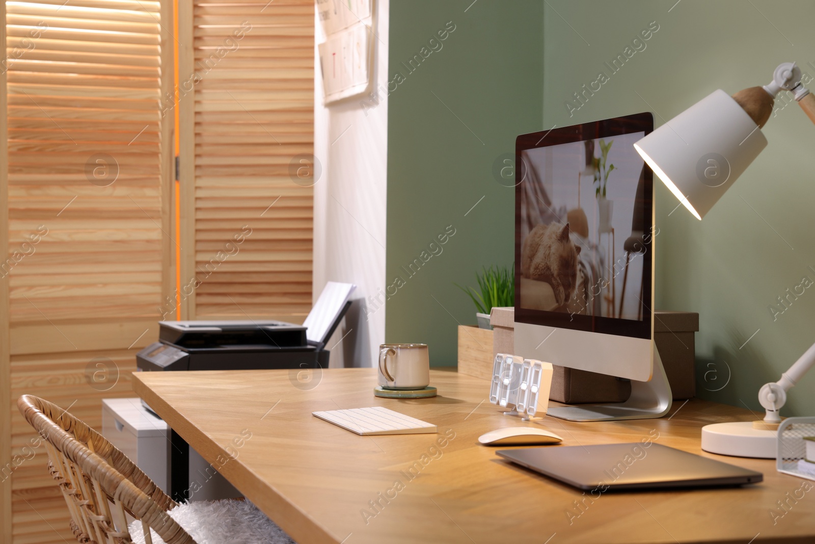 Photo of Stylish workplace with computer, laptop and lamp near olive wall at home