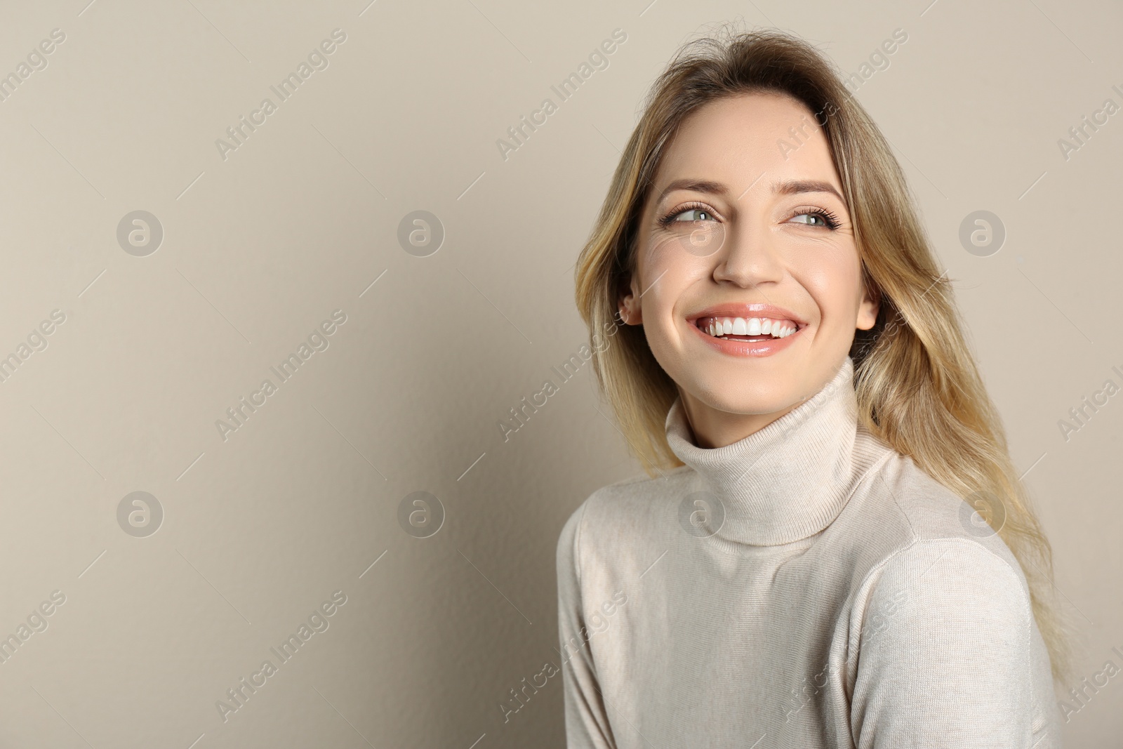 Photo of Portrait of happy young woman with beautiful blonde hair and charming smile on beige background. Space for text