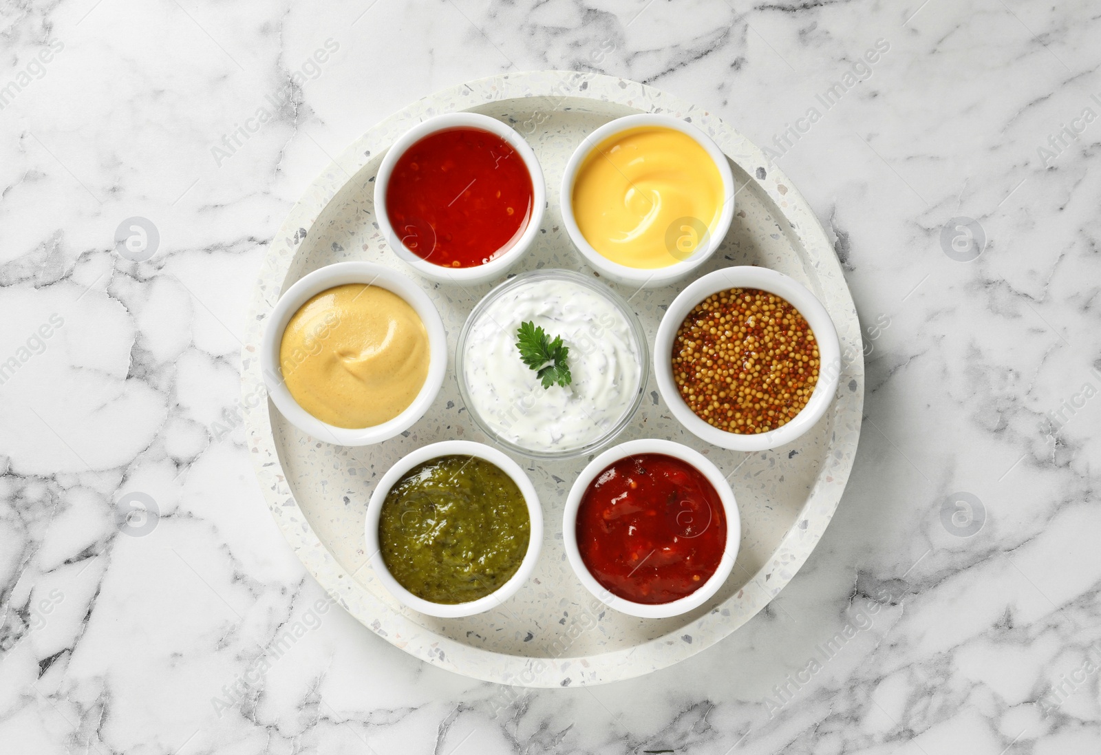 Photo of Set of different delicious sauces on white marble table, top view