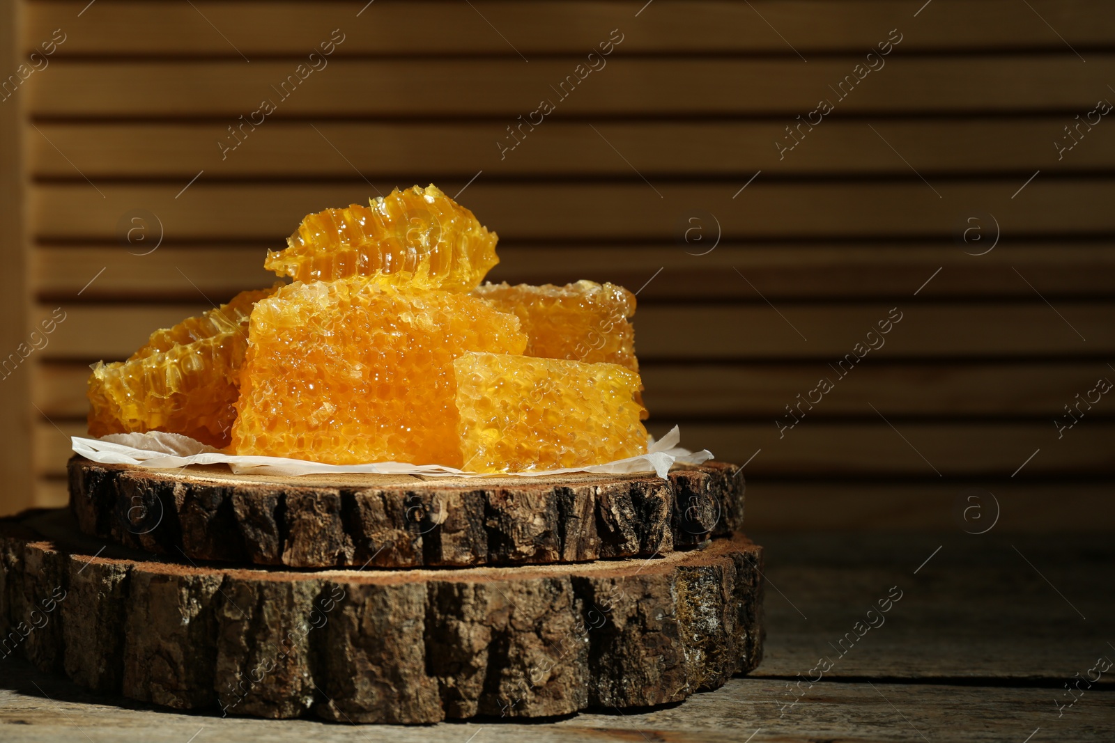 Photo of Natural honeycombs and wooden dipper on rustic table, space for text